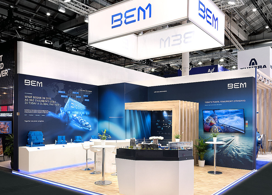 Messestand der Firma BEM anlässlich der SMM 2026 in Hamburg Messestand auf der SMM 2026 in Hamburg mit einem großem Textilbanner abgehangen von der Hallendecke, grossformatigen maritimen Drucken auf der Wand, eine Sitznische mit Holzbaldachin aus unserer Tischlerei, Laminatboden Holzoptik